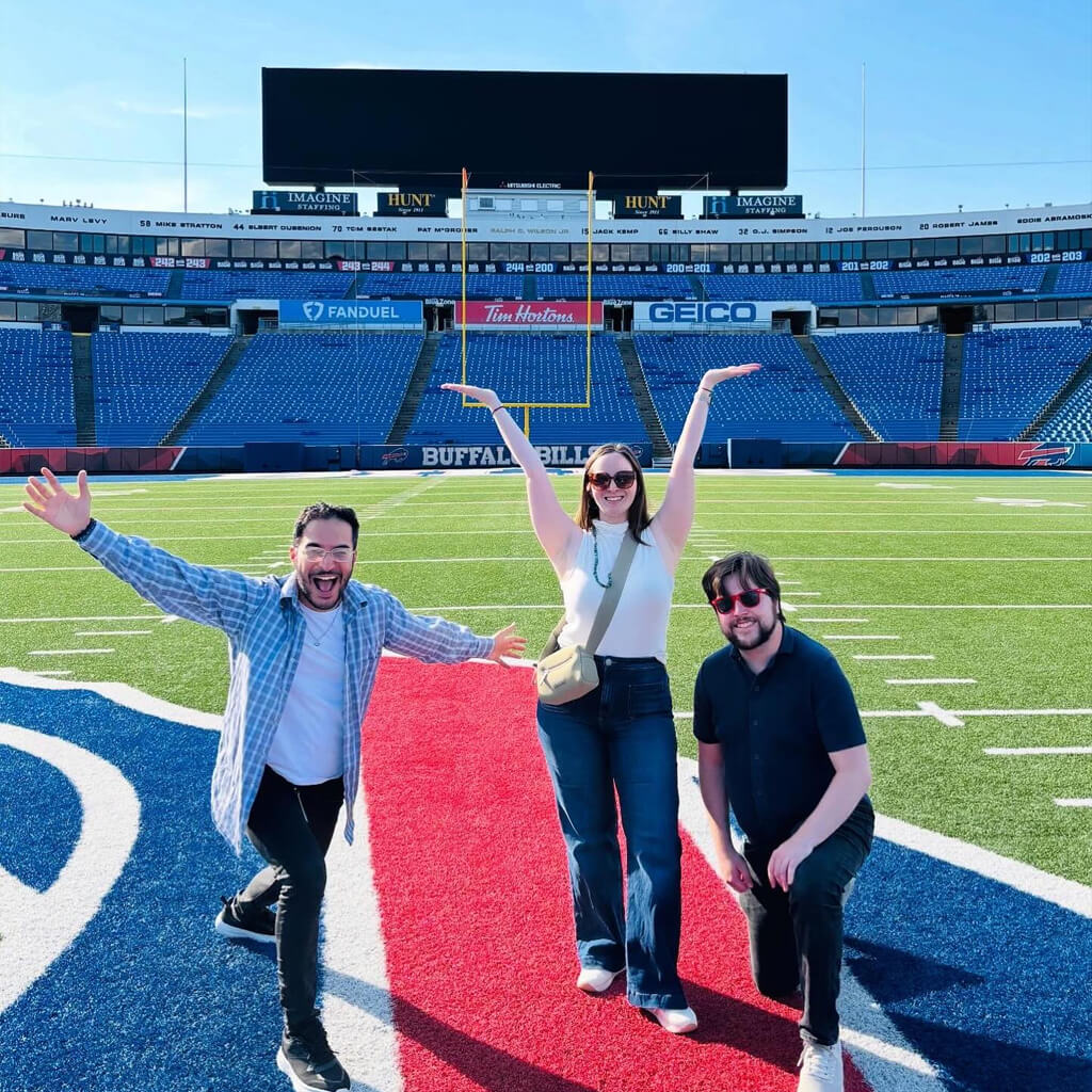 Social media post of two men and a woman stand proudly on the Buffalo Bills football field, smiling with their arms up in celebration