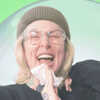 A woman laughs while wiping her face with a wet wipe